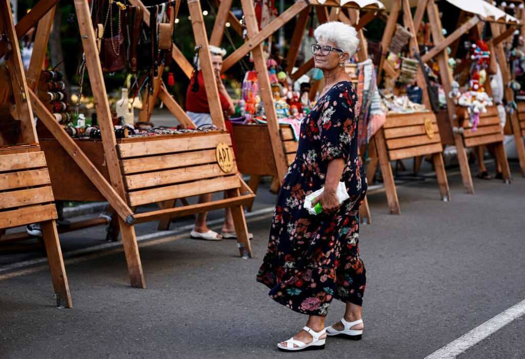 A woman strolls past market stalls at a fair.