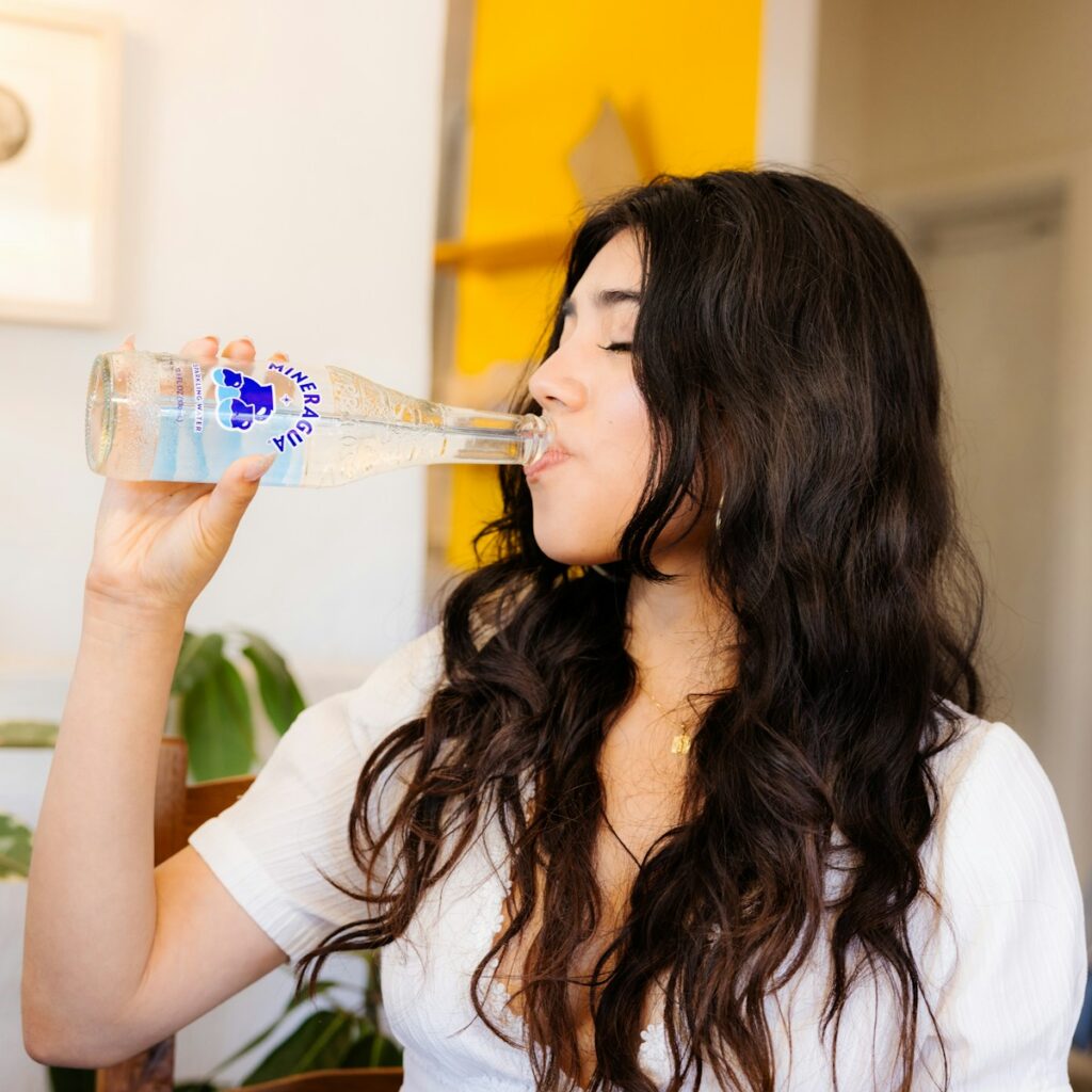 a woman drinking water from a plastic bottle