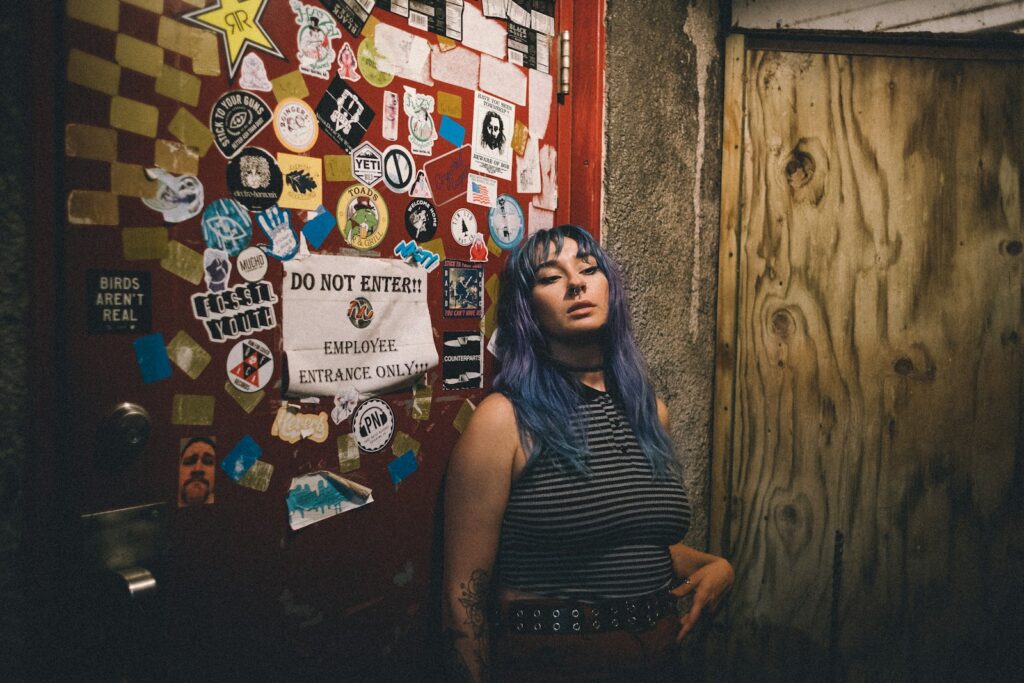 a woman with blue hair standing in front of a door