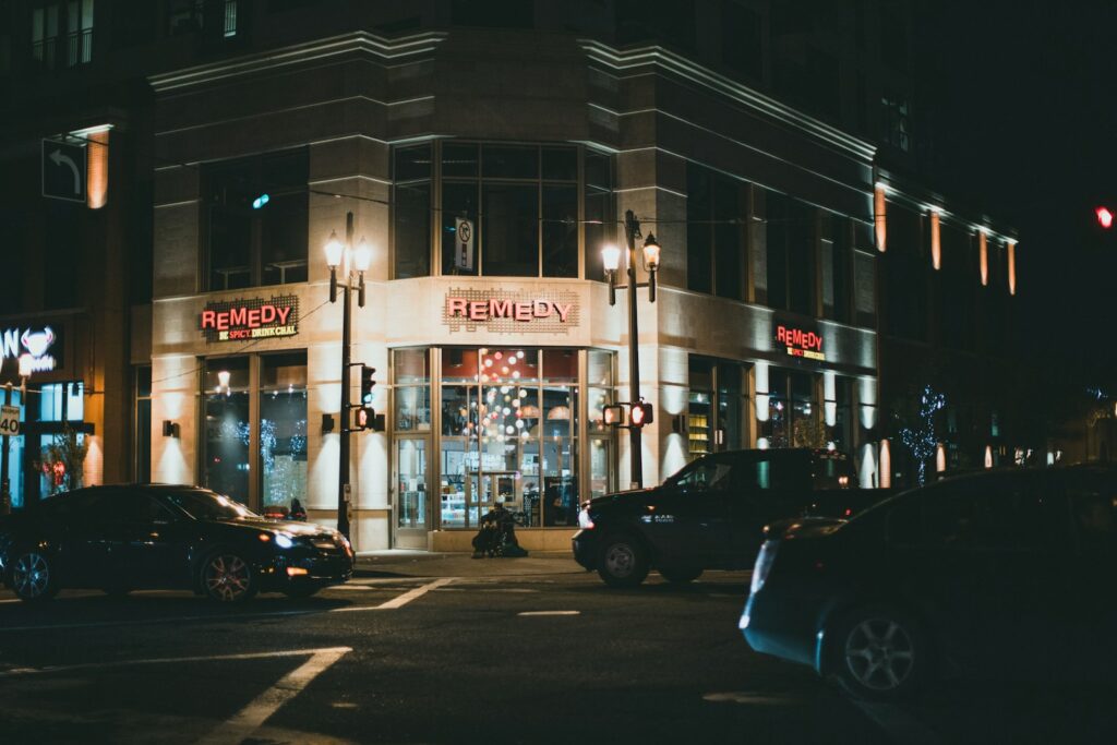 a city street at night with cars parked on the side of the street