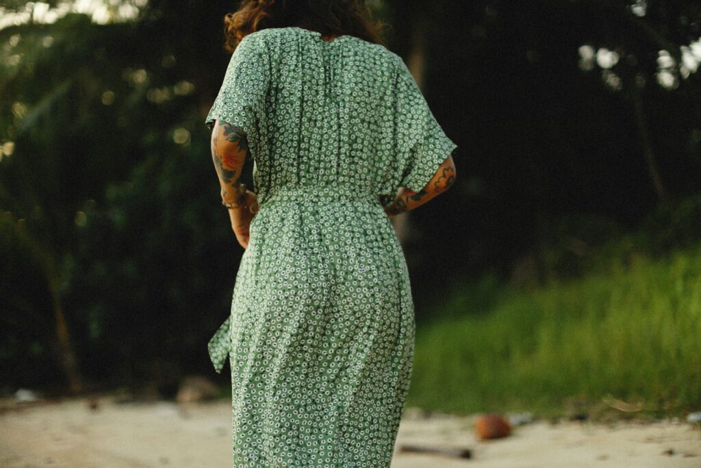 a woman in a green dress walking down a dirt road