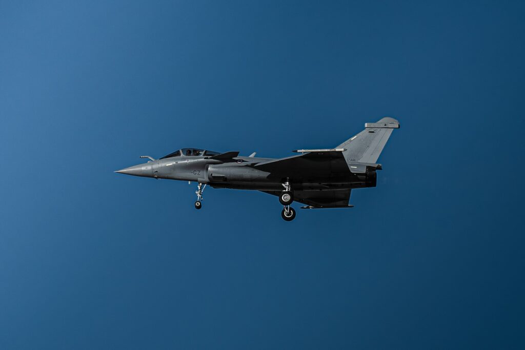 a fighter jet flying through a blue sky