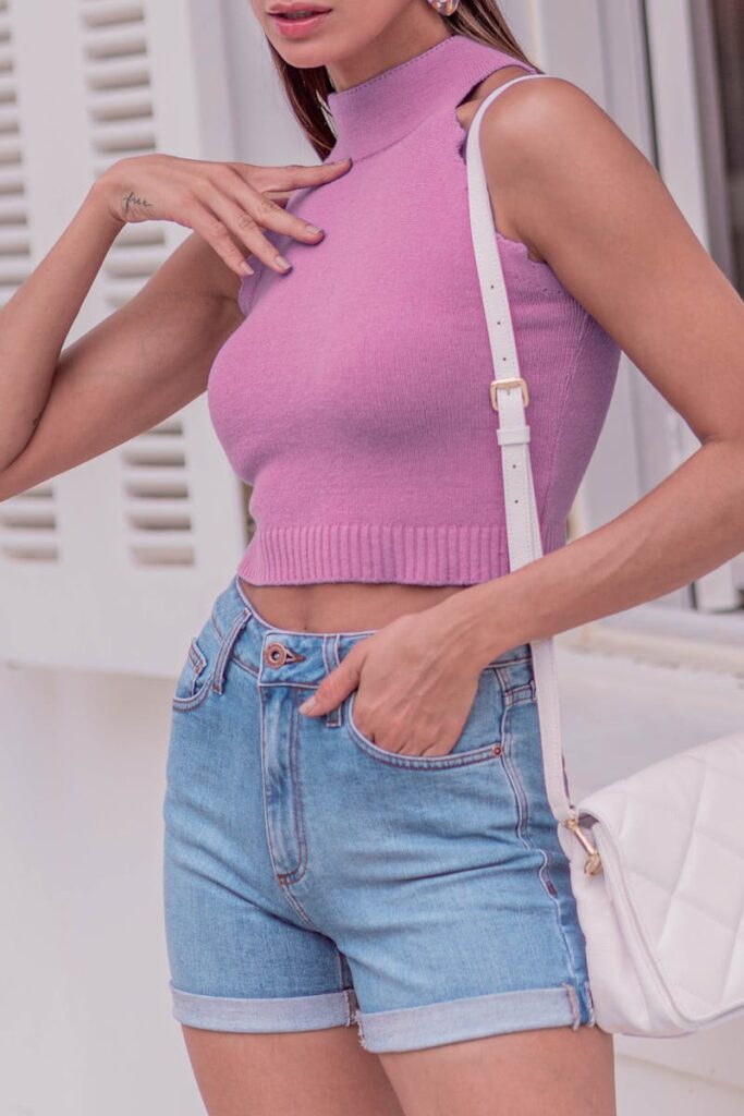 Stylish woman in pink sleeveless top and denim shorts showcasing a casual summer outfit.