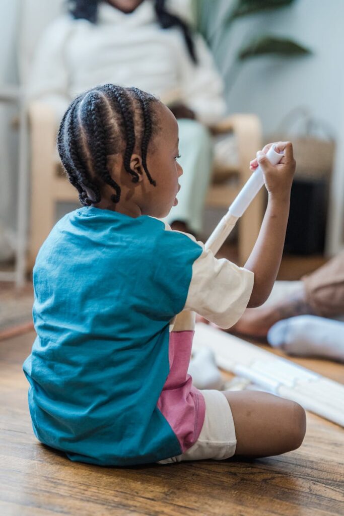 Young boy with cornrows playing creatively with tubes indoors.