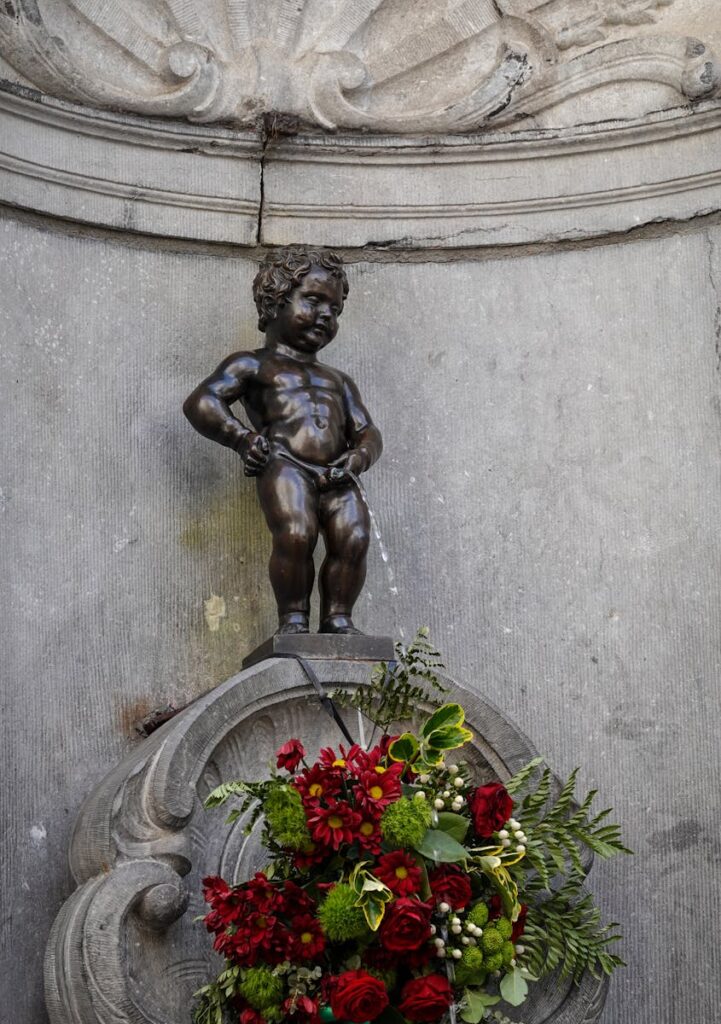 Iconic Manneken Pis statue in Brussels adorned with vibrant flowers, a must-see landmark.