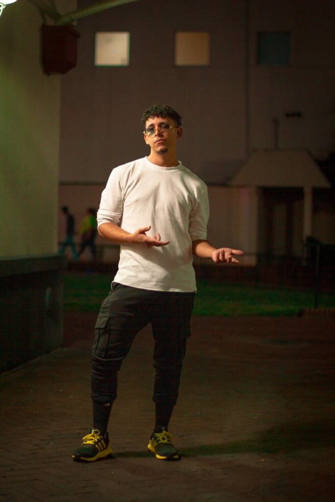 Stylish man with curly hair posing confidently at night in a fashionable outfit.