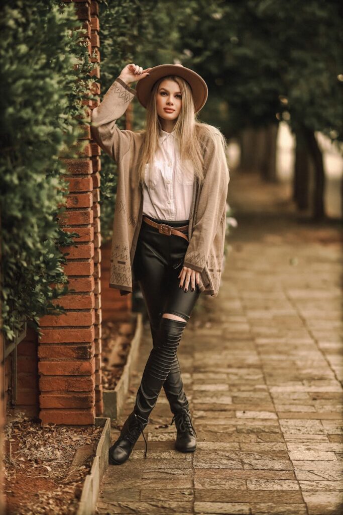 Elegant woman in fashionable attire posing stylishly on a cobblestone sidewalk.