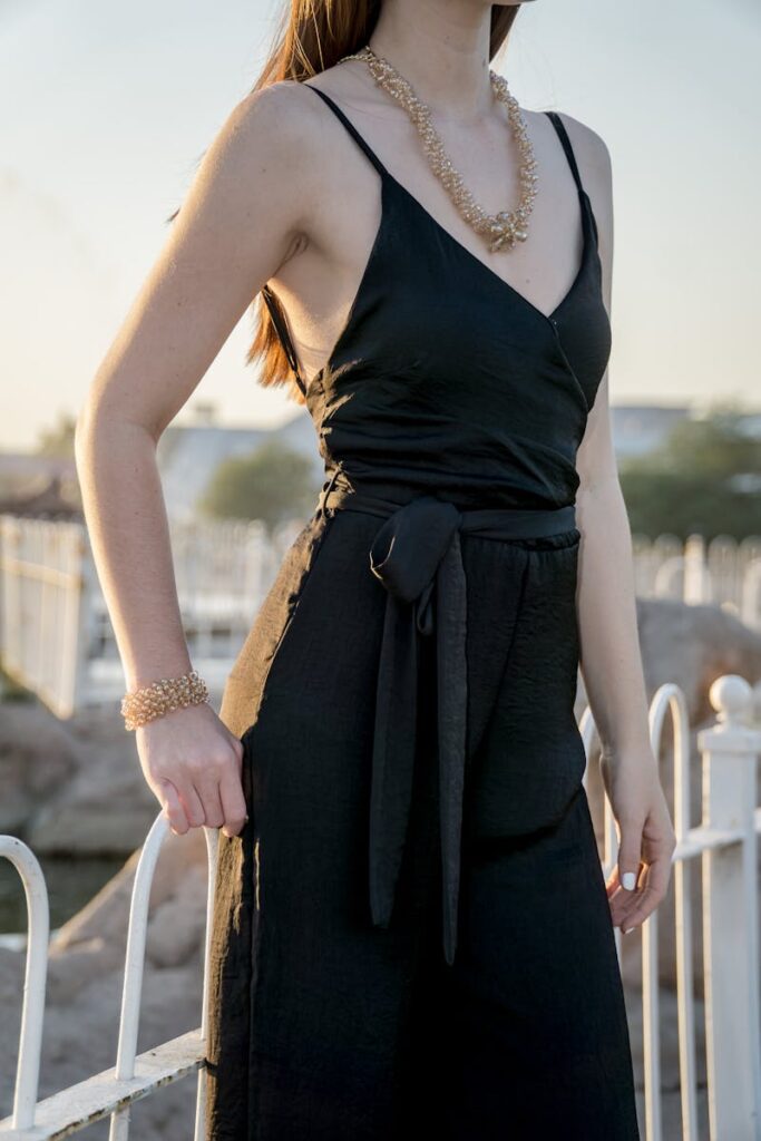 Stylish woman in a black dress posing outdoors, showcasing elegant fashion.