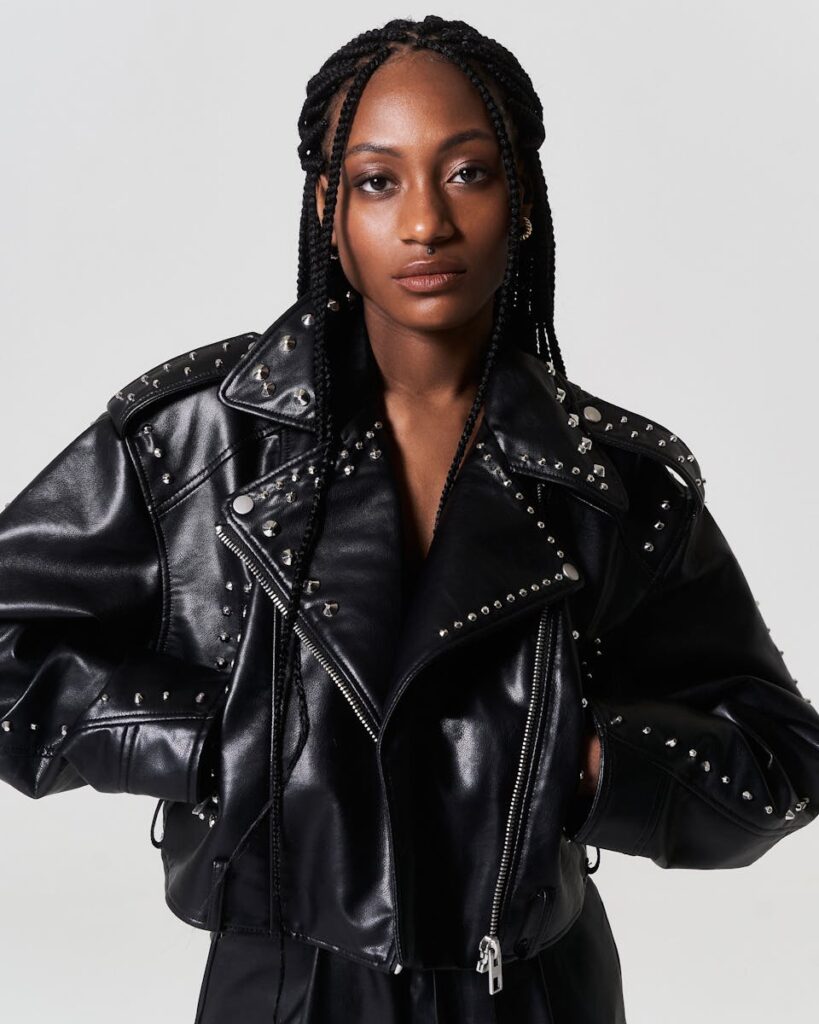 Stylish portrait of a young woman in a studded leather jacket, posing confidently.