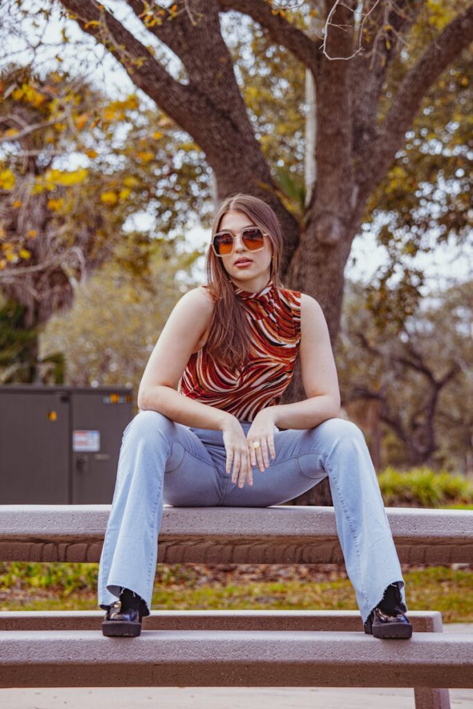 Chic young woman with sunglasses sitting on a park bench in Tampa, exuding a playful and relaxed vibe.
