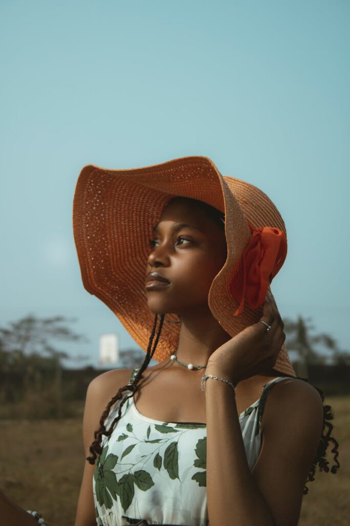 Portrait of a woman wearing a sun hat, exuding elegance in an outdoor setting.