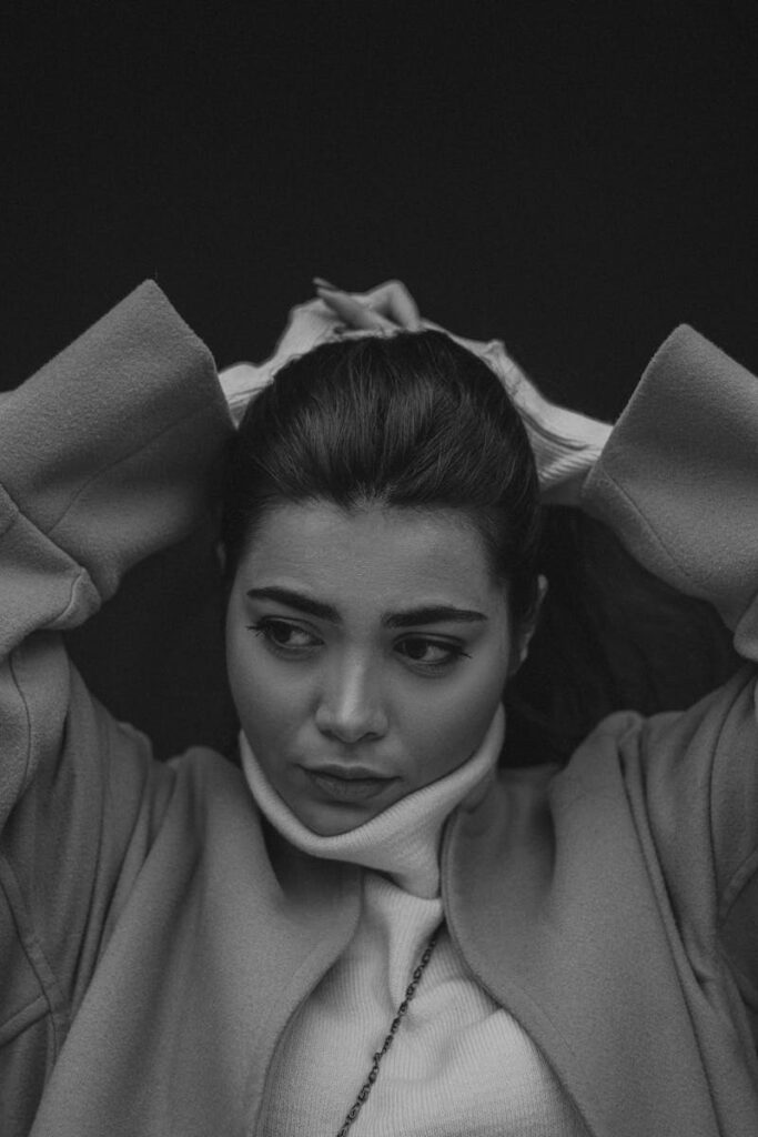 Elegant black and white portrait showcasing a woman in a turtleneck and coat.