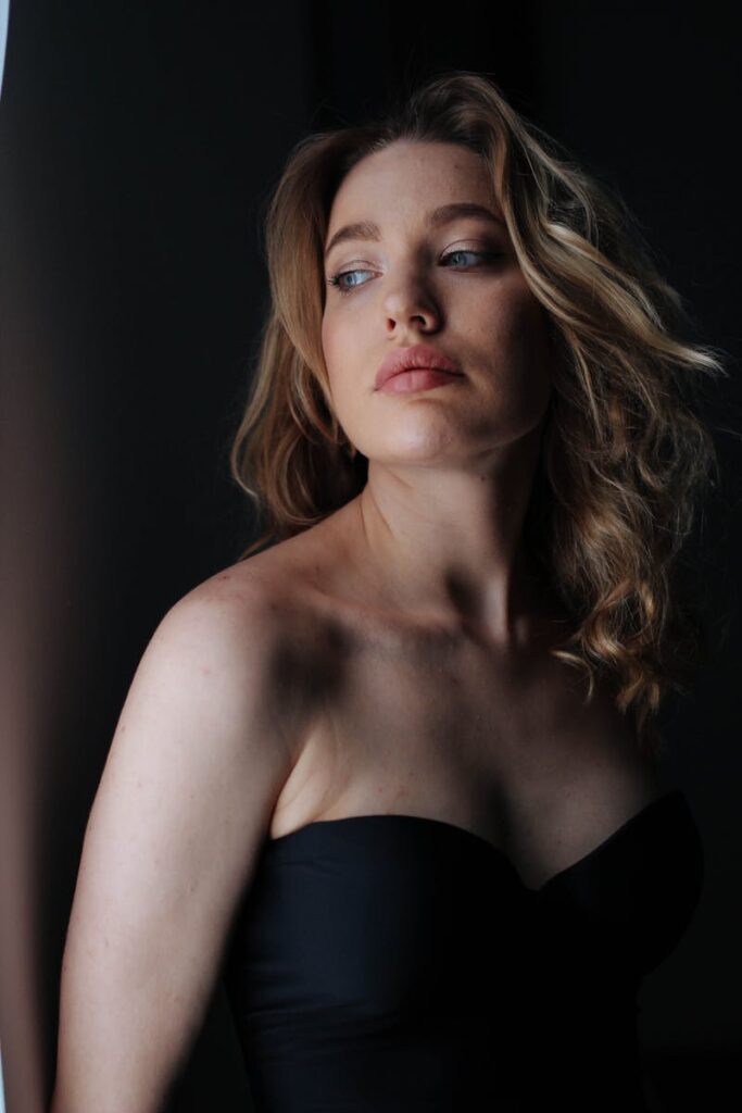 A thoughtful woman in a black strapless top, looking away from the camera.