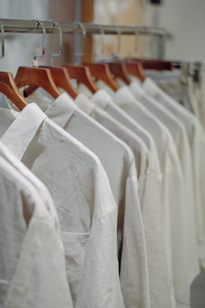 Close-up of neatly arranged white shirts hanging on wooden hangers indoors.