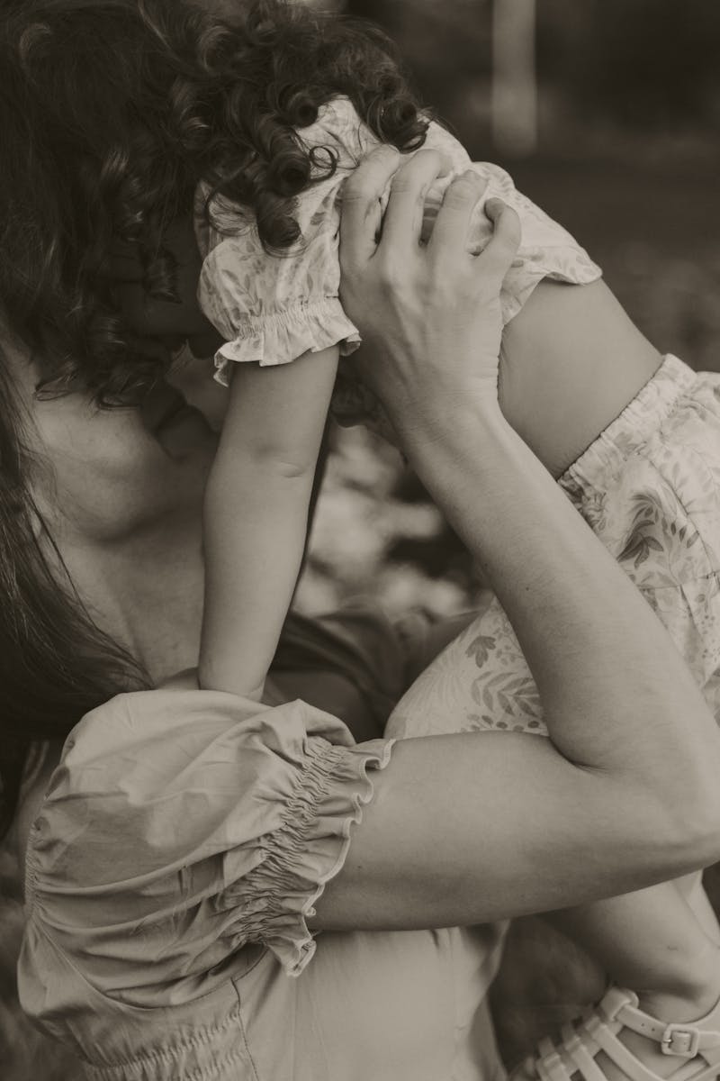A tender moment captured in sepia tones of a mother holding her child close outdoors.