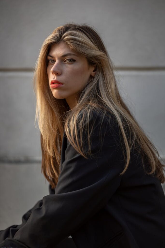 A sophisticated portrait capturing a young caucasian woman with long blonde hair in a thoughtful pose.