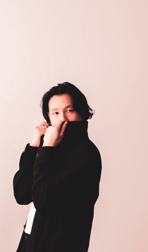 A fashion-forward man poses stylishly in a black jacket during a studio shoot.