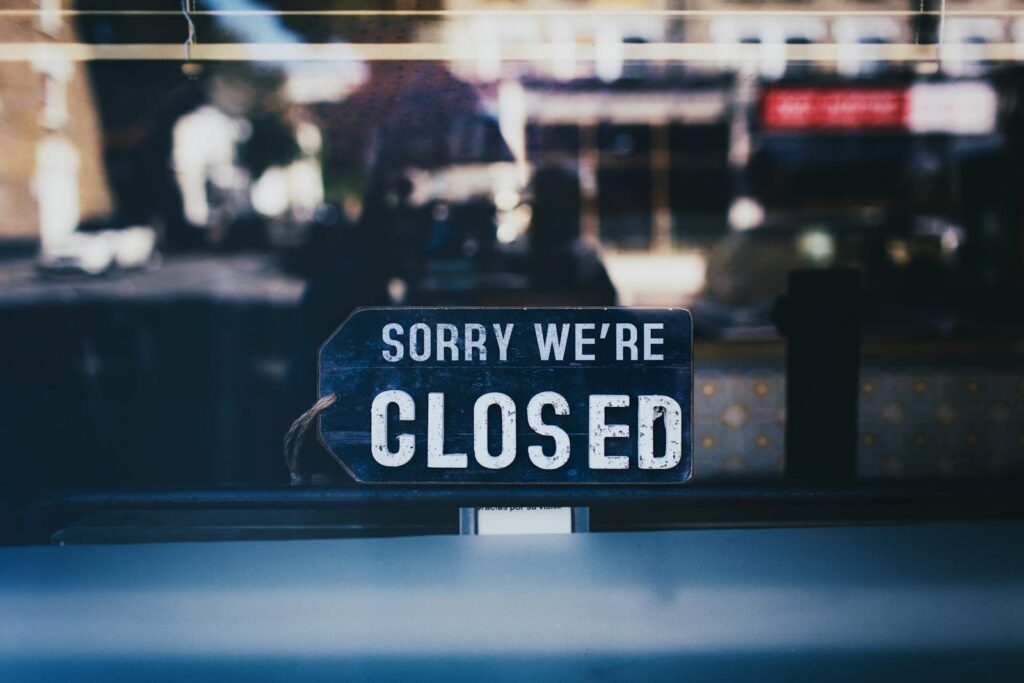 Moody image capturing a 'Sorry We're Closed' sign in a London shop window.