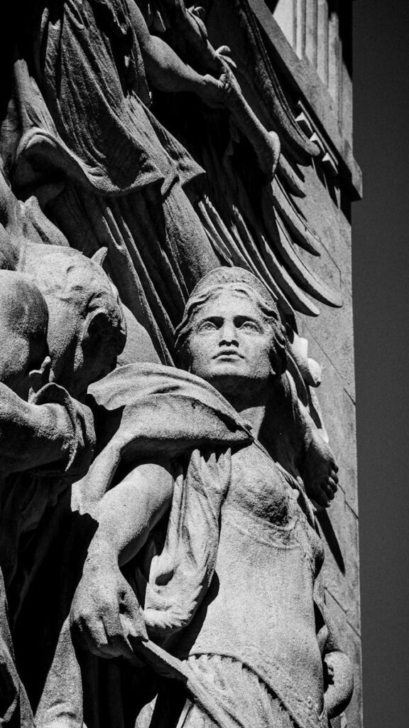 Dramatic stone sculpture depicting a strong woman warrior in detailed relief.