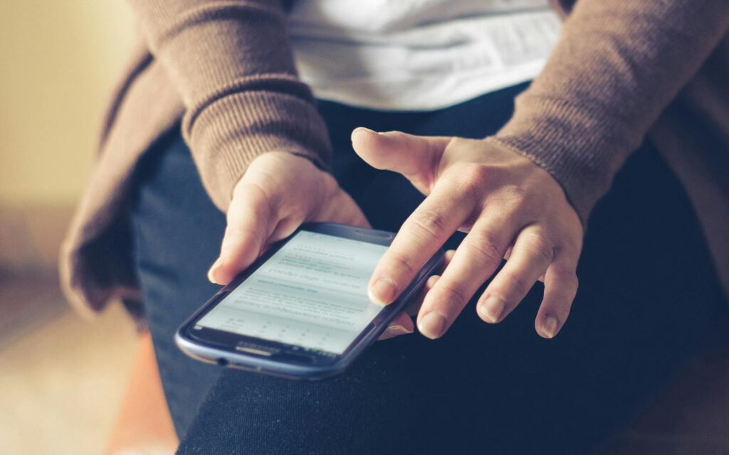 Close-up of adult using smartphone indoors, browsing web with focus on screen.