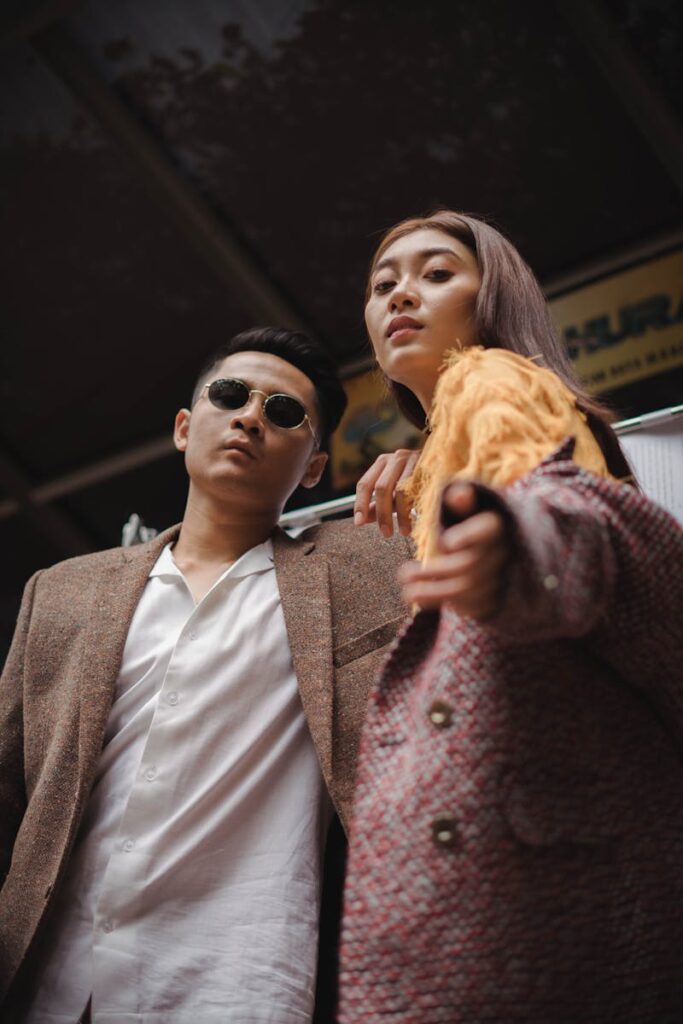 Stylish man and woman pose confidently in fashionable outerwear in a low angle urban shot.