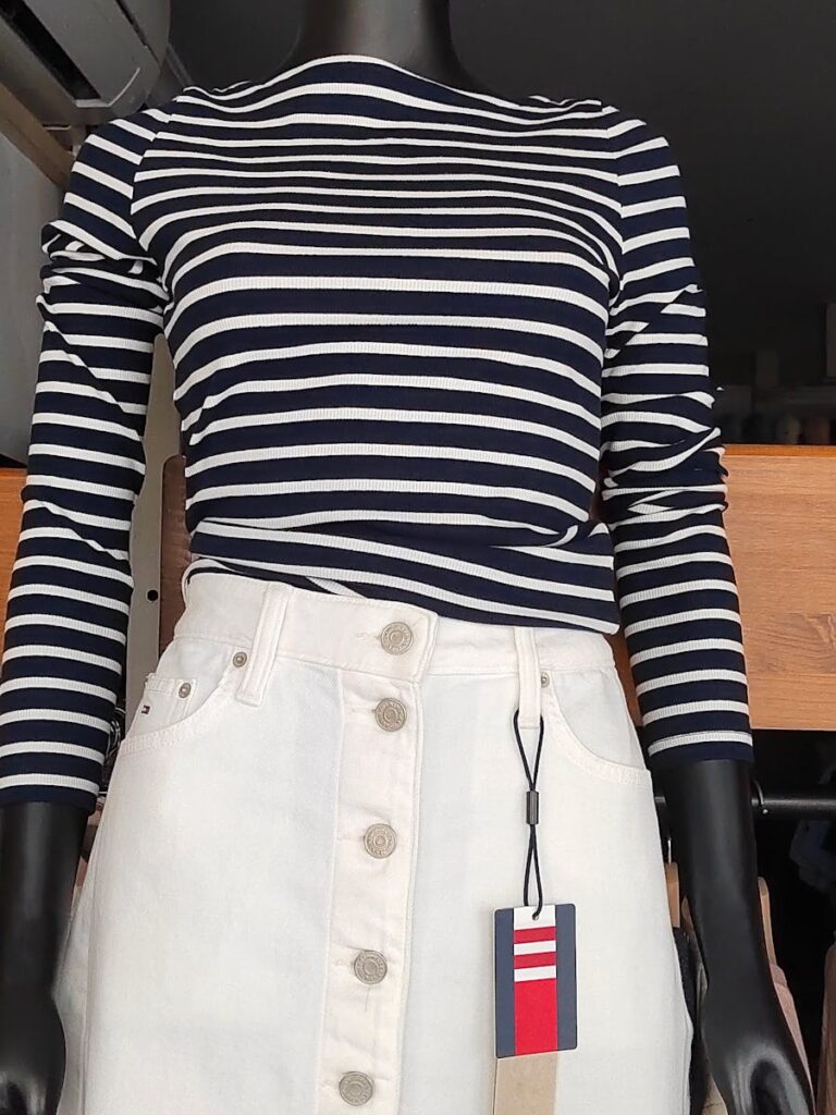 Mannequin displaying a blue and white striped blouse with a white denim skirt.