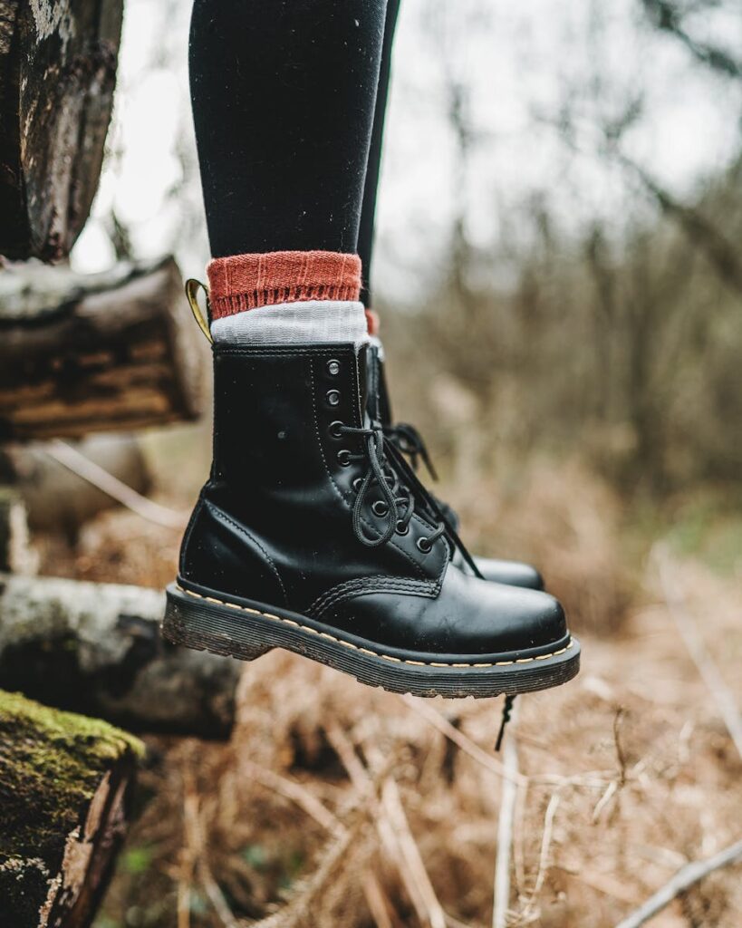 Stylish black leather boots on a tree stump, perfect for outdoor adventures.