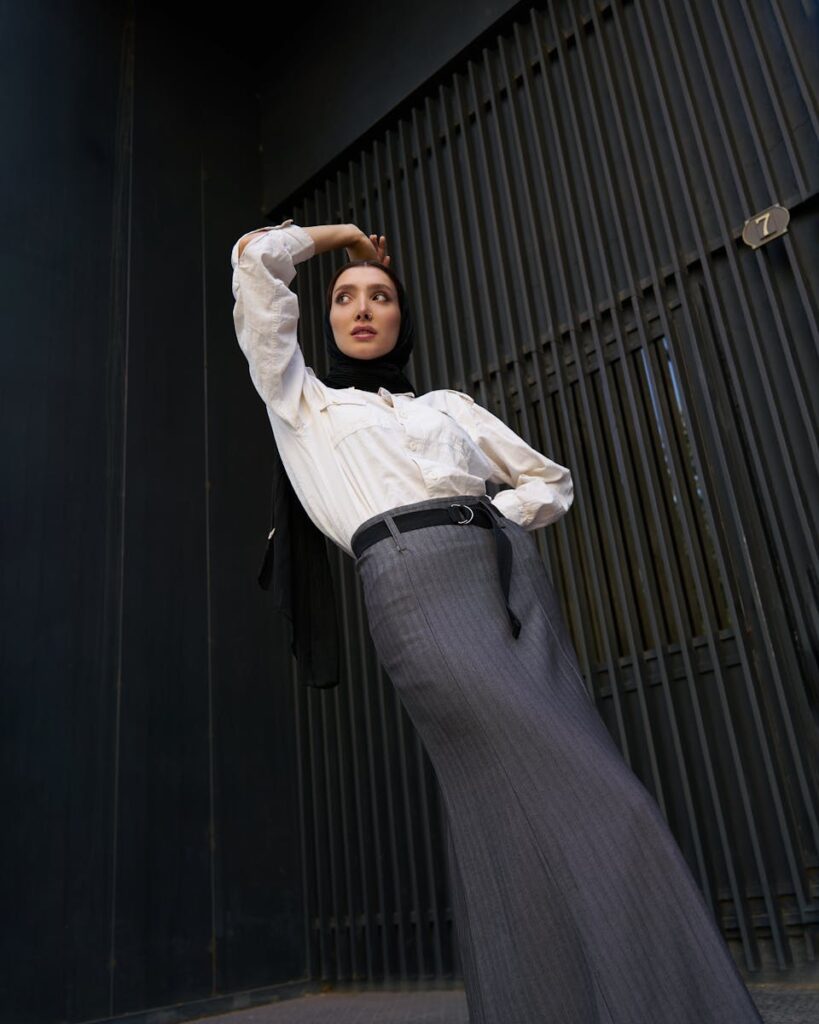 Stylish woman in black hijab and white shirt posing outdoors, showcasing modern fashion.