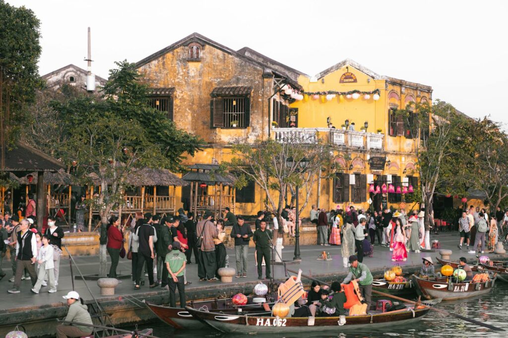 Colorful Hoi An riverside with people and traditional boats during a festival.