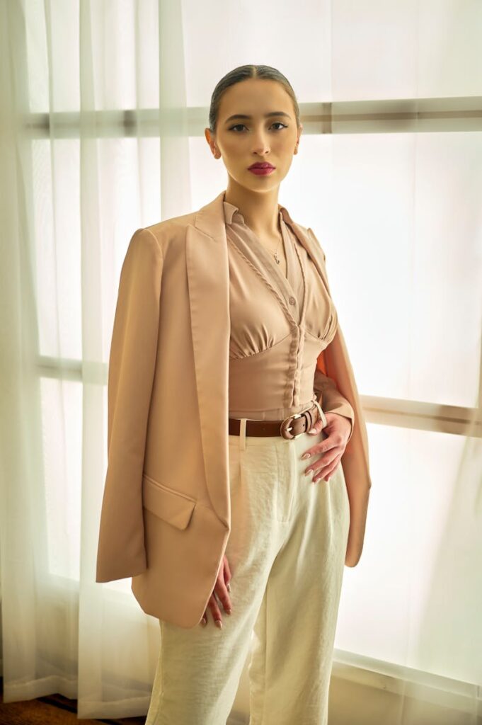 Young woman posing confidently in chic neutral clothing indoors with natural light.