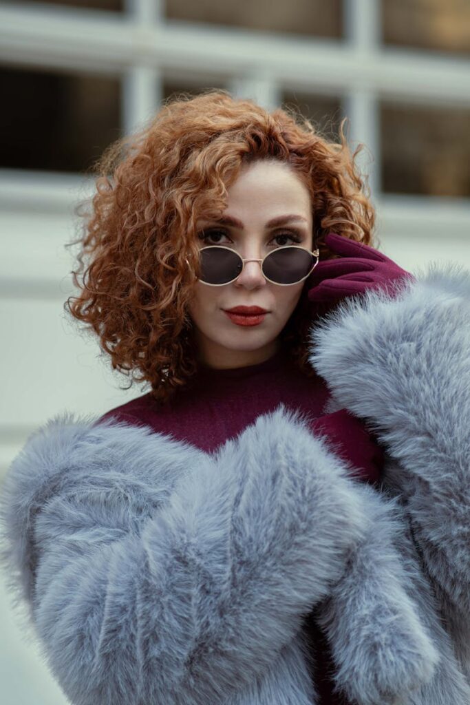 Stylish woman in sunglasses and faux fur coat, balancing winter elegance and modern fashion.