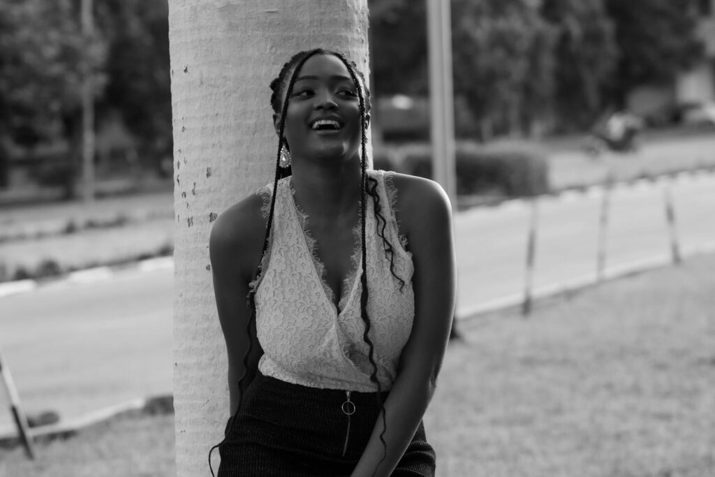 Elegant black and white portrait of a woman leaning against a tree outdoors.
