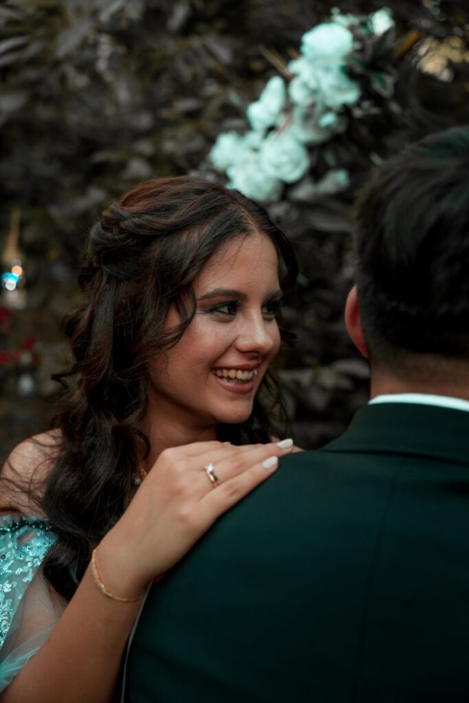 Smiling woman holding partner's shoulder during festive outdoor event.