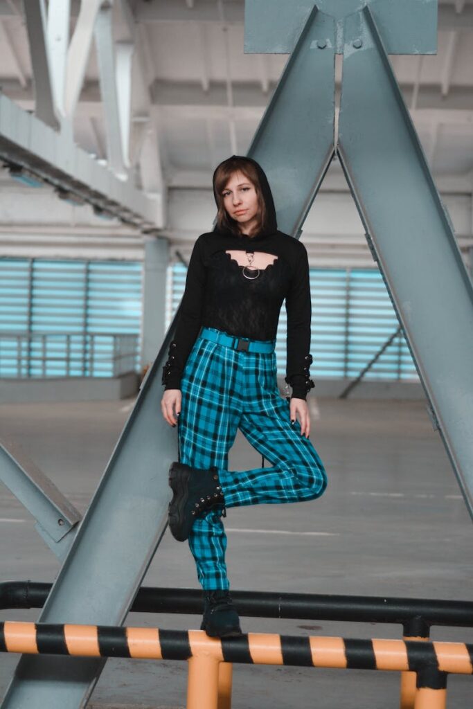 Stylish woman in modern plaid outfit against industrial backdrop.