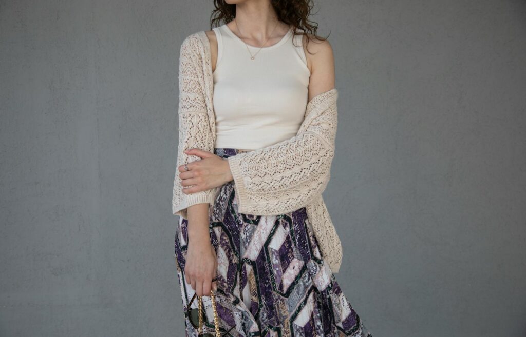 Elegant woman in a knitted cardigan and patterned skirt displaying modern fashion.