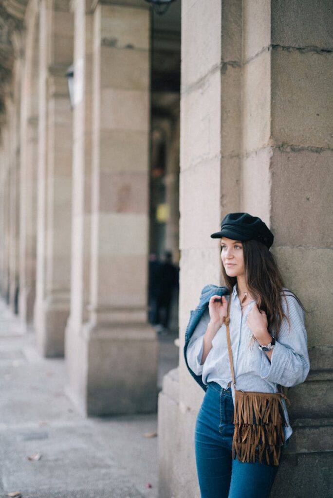 Stylish woman leaning against a column in a modern urban setting, showcasing effortless elegance.