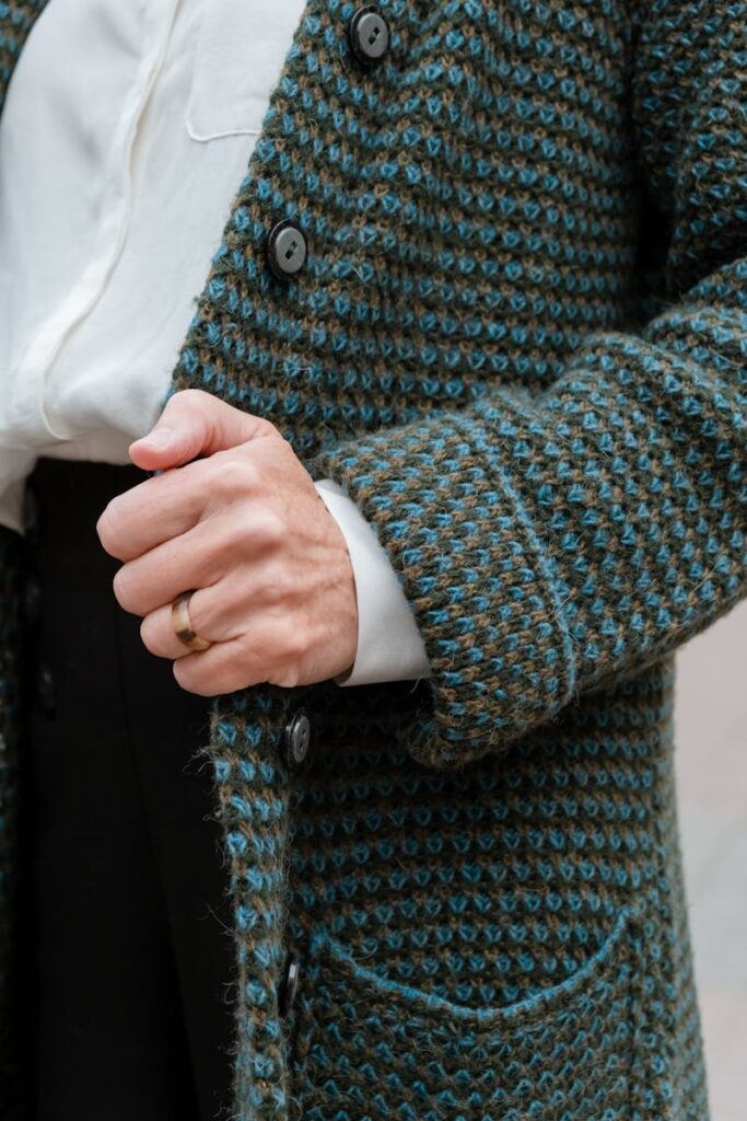 Detailed view of a stylish knit coat with gold ring, showcasing fashion elegance.