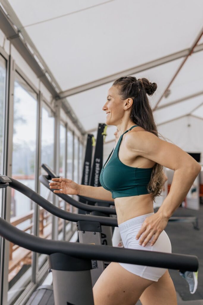 Fit woman jogging on treadmill in an airy gym, focused on health and fitness.