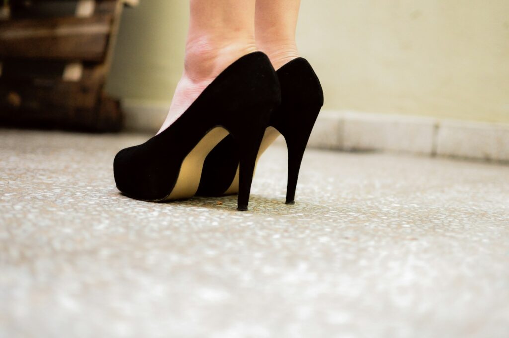 Black high heels on a tiled floor.