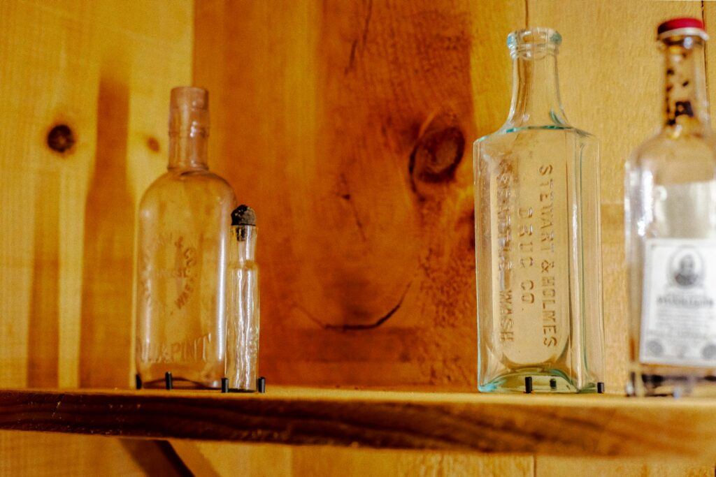 clear glass bottle on brown wooden shelf