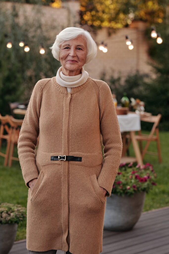 Cheerful senior woman in a cozy cardigan enjoying an outdoor gathering in the garden.