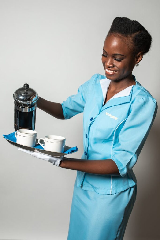 Flight attendant in blue uniform serving coffee with a smile, showcasing hospitality.