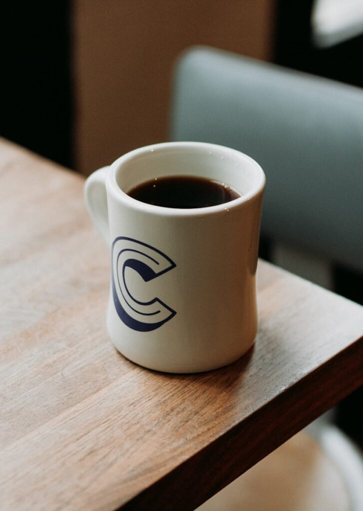 white ceramic mug with black liquid on table