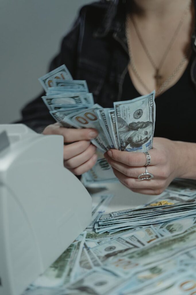 A woman counting cash with a money counter, symbolizing financial management.