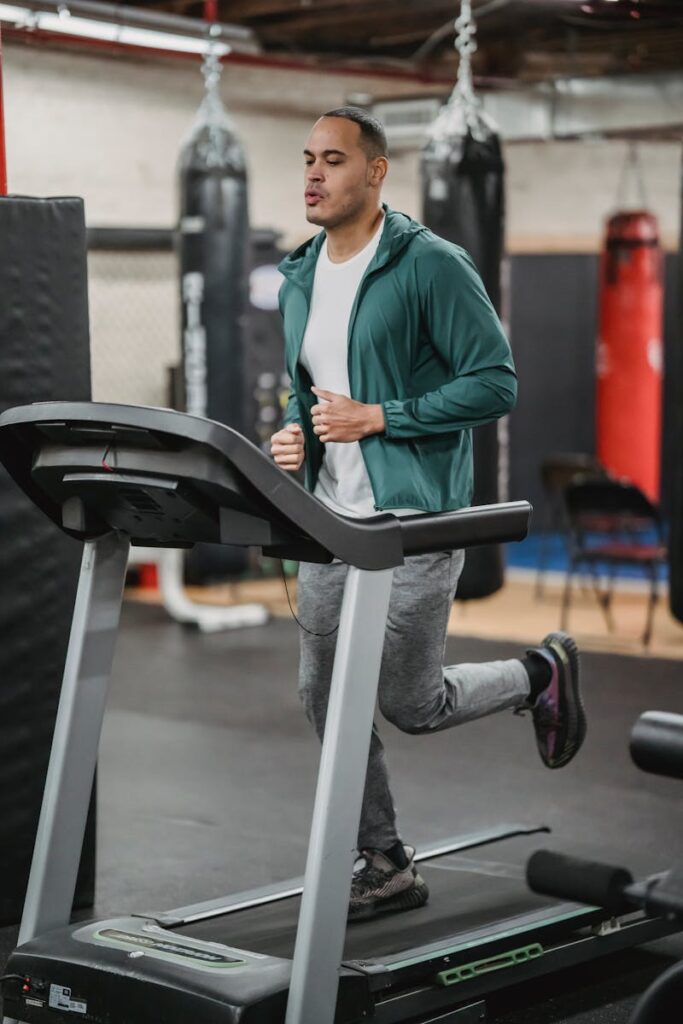Adult male exercising on treadmill in a modern gym. Focused fitness workout indoors.