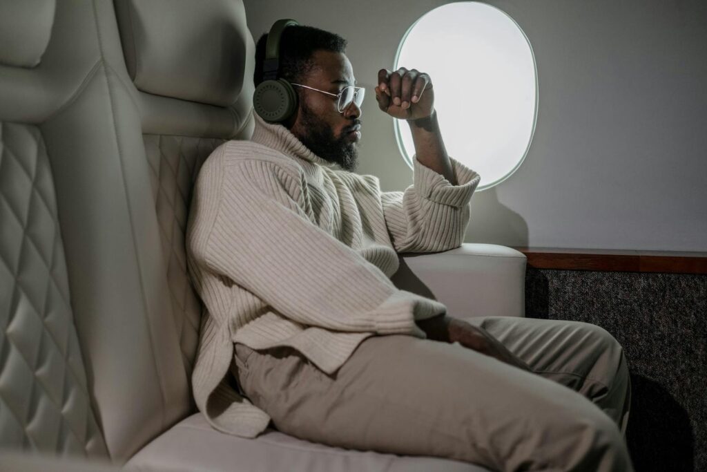 A man relaxing with headphones while traveling on a plane, enjoying leisure in comfort.