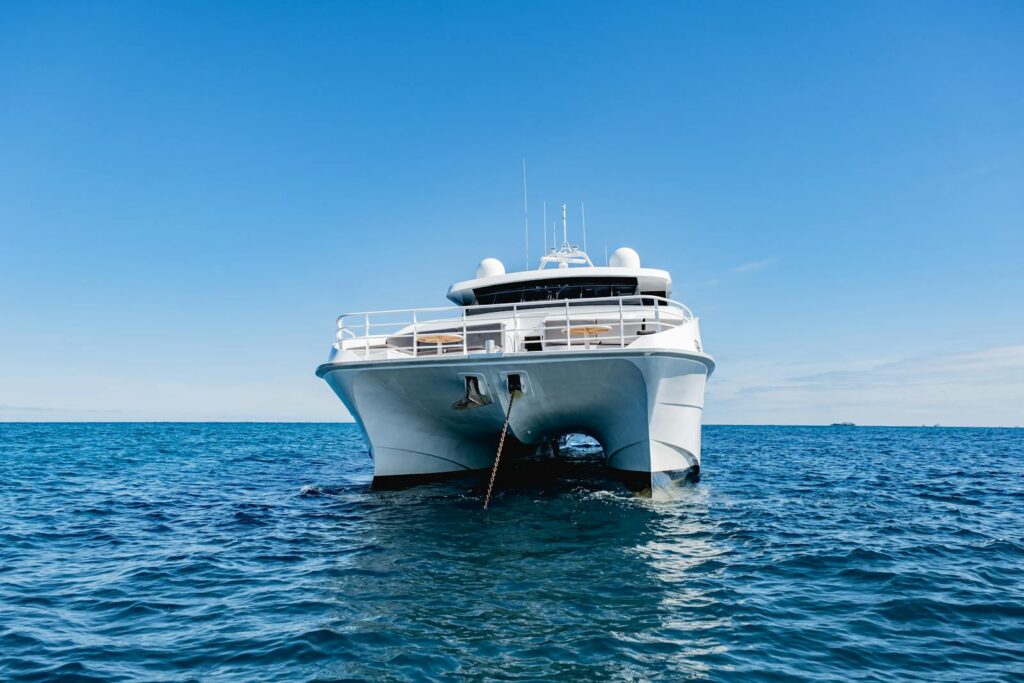 Front view of a luxurious yacht anchored on a clear blue ocean under a vibrant sky.