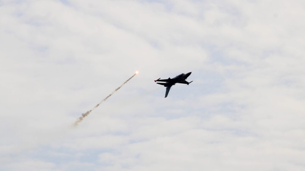 A jet flying through a cloudy blue sky