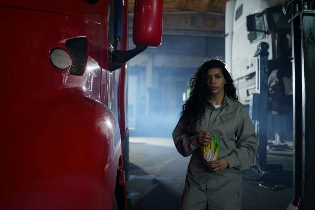 Portrait of a female mechanic in a garage holding tools, showcasing empowerment and skill in automotive work.