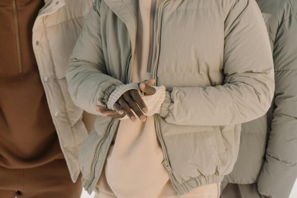 Close-up of fashionable puffer jackets with layered winter clothing on diverse individuals.